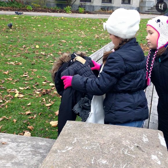 Deux fillettes déposant une doudoune sur un banc