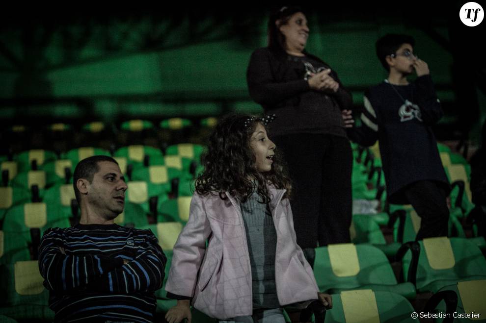   Dans les tribunes du stade, de jeunes spectateurs assistent au match en compagnie de leurs parents.  