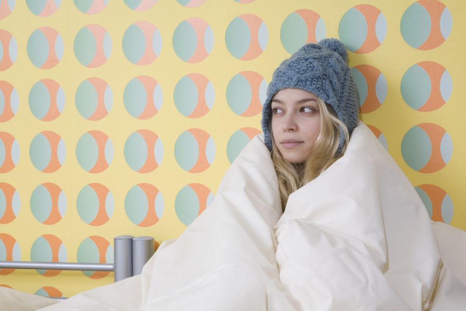 Photo d'illustration d'une femme ayant froid dans sa chambre.