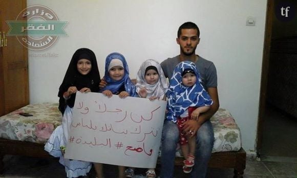 Un père de famille pose devant ses filles voilées avec le slogan de la campagne.