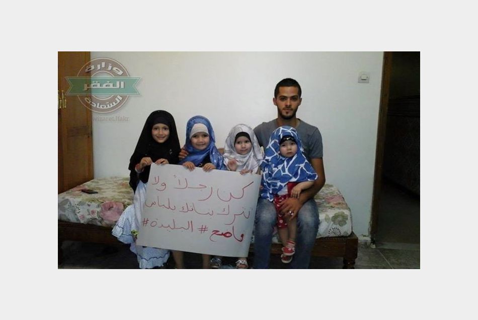 Un père de famille pose devant ses filles voilées avec le slogan de la campagne.