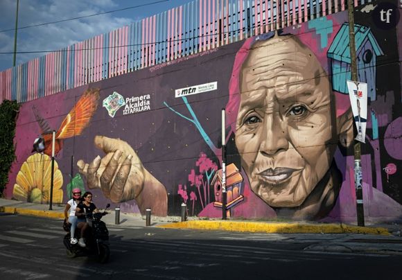 Des femmes passent à moto devant une peinture murale sur les Mexicaines, à Mexico le 1er juin 2024