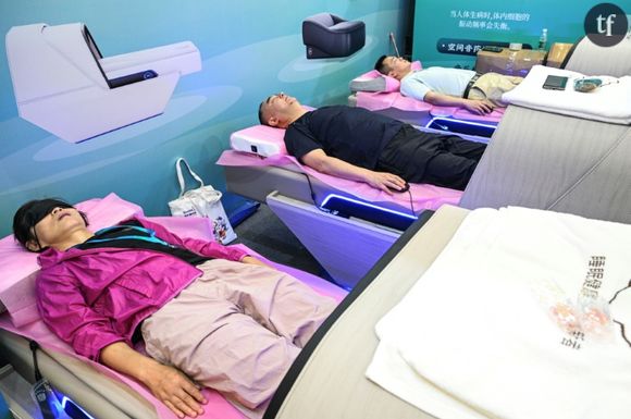 Des visiteurs font une sieste en testant une cabine de sommeil lors d'un salon dédié aux séniors à Shangaï, en Chine, le 13 juin 2024