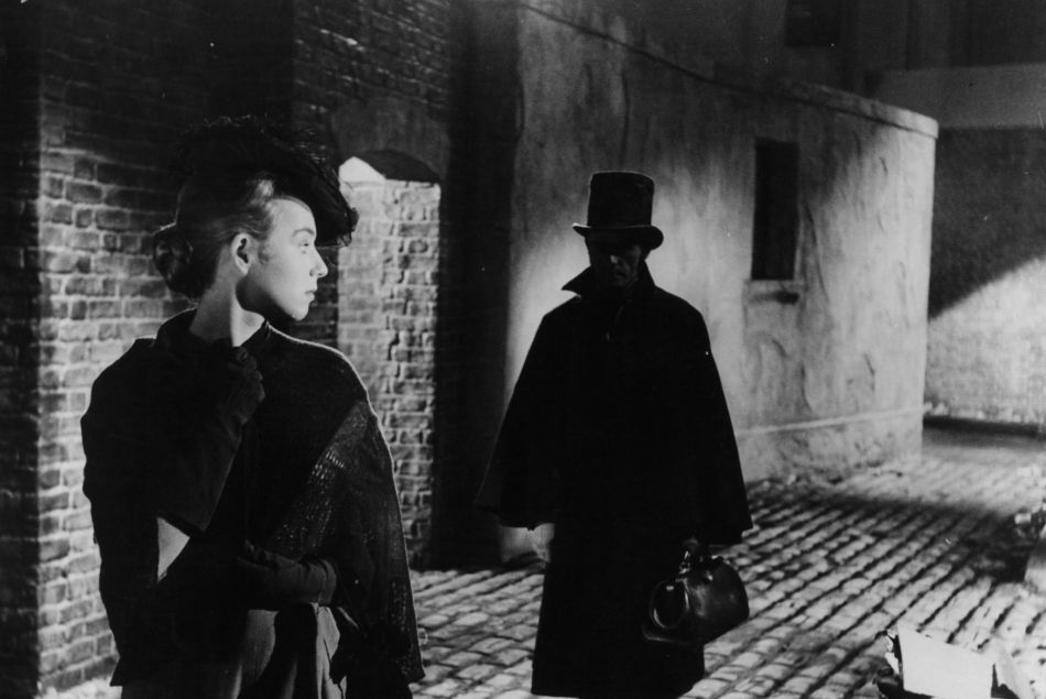 Une femme suivie par un homme dans le film "Jack l'éventreur" (1959)