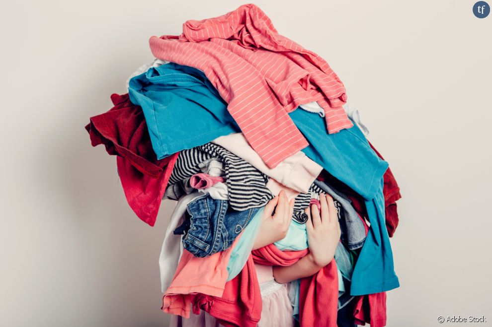 Un enfant sous une pile de vêtements
