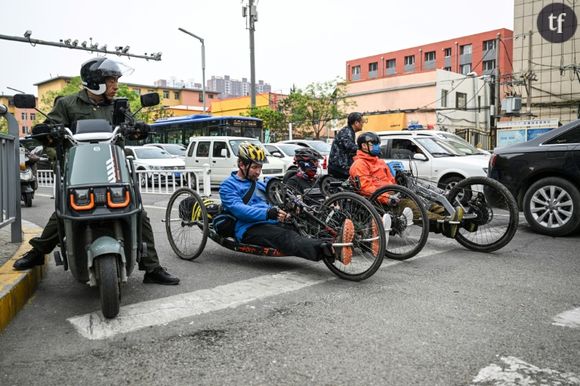 Le 5 mai 2024, Pan Yifei (d), Wang Feng (c) et Joshua Dominick (g) au guidon de leurs vélos à main, dans la circulation à Hohhot, en Mongolie intérieure, dans le nord de la Chine