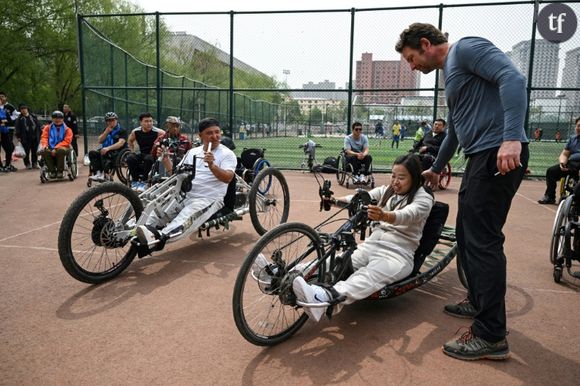 Joshua Dominick (d) fait une démonstration de vélos à main à des membres d'une association de personnes handicapées dans un parc de Hohhot, dans la région de Mongolie intérieure, dans le nord de la Chine, le 5 mai 2024