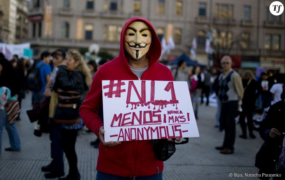 Un homme masqué tient un panneau &quot;Pas une de moins. Plus jamais. Anonymous&quot;.