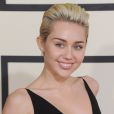 Miley Cyrus plaque ses cheveux vers l'arrière pour dégager son visage.