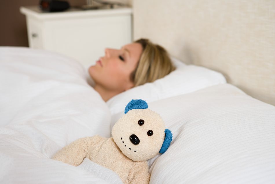 Une femme dort seule à côté d'un ours en peluche.