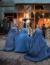 En Afghanistan, des femmes en burqa mendient devant une boulangerie.