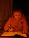 Alevtyna, 8 ans, fait ses devoirs à la bougie pendant une coupure de courant provoquée par les attaques de missiles de la Russie contre les infrastructures critiques de l'Ukraine, à Uzhhorod, le 30 novembre 2022.