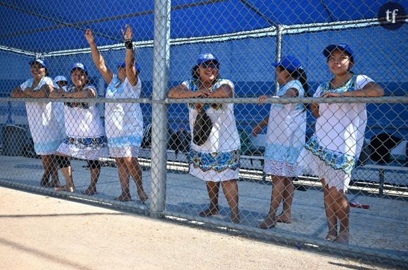 Des membres de "Las Amazonas de Yaxunah", une équipe féminine de softball de la région du Yucatan, au Mexique, jouant pieds nus et en robes traditionnelles, regardent leur équipe lors d'un match amical contre l'équipe féminine de softball du lycée de Walnut, le 31 mai 2024 en Californie