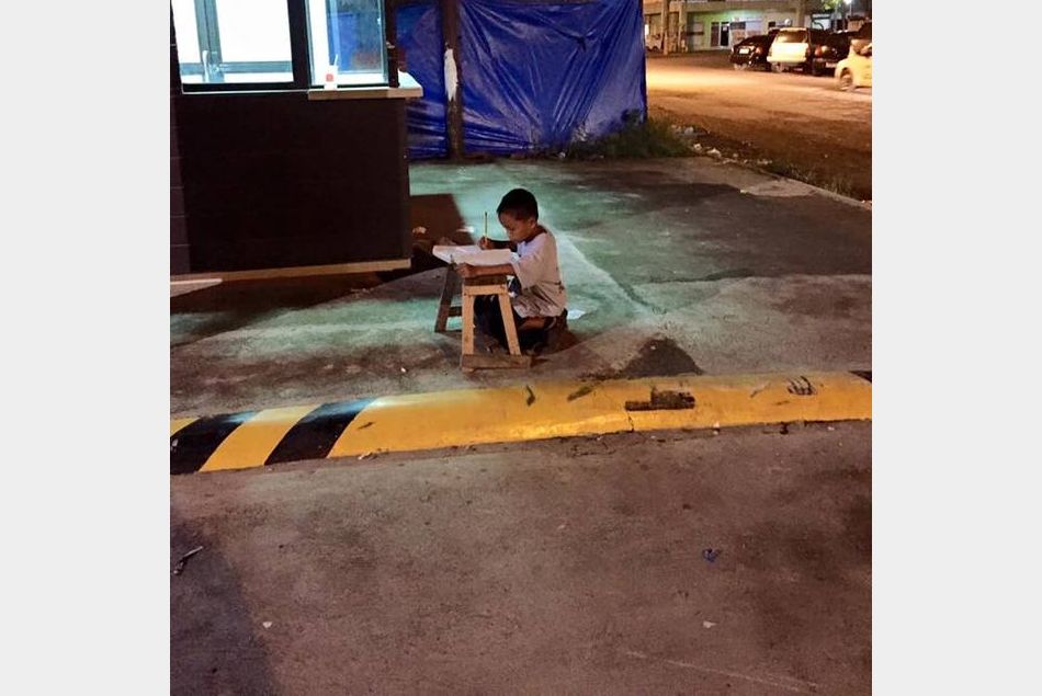 Le petit Daniel fait ses devoirs dans la rue sur lîle de Cebu, aux Philippines.
