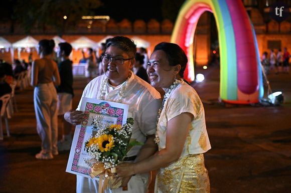 Le couple queer birman Nyan (g) et Mae pose pour une photo, avec leur certificat de mariage sans valeur officielle, reçu lors de la marche des fiertés de Chiang Mai, en Thaïlande, le 26 mai 2024